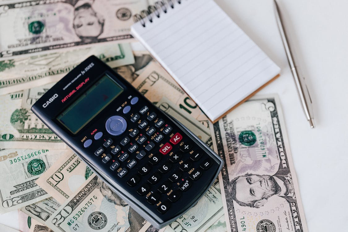 A calculator, notepad, pen, and cash while budgeting for a new swimming pool